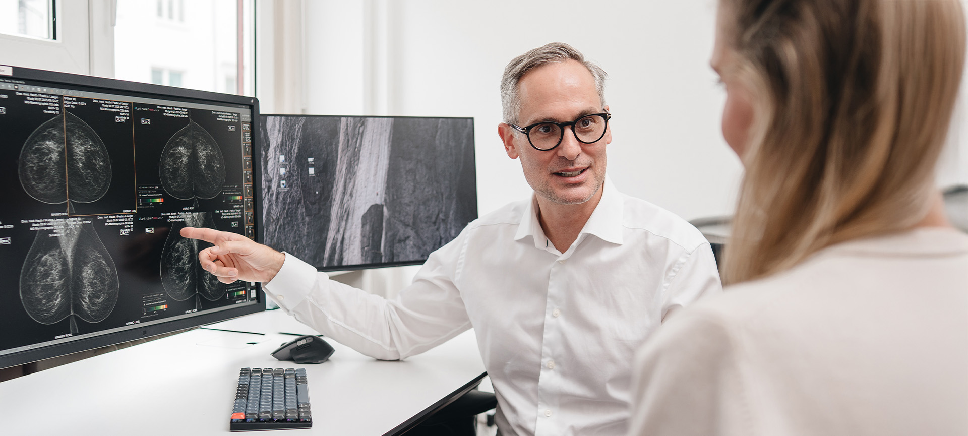Ein Arzt erklärt einer Patientin den Befund am Monitor